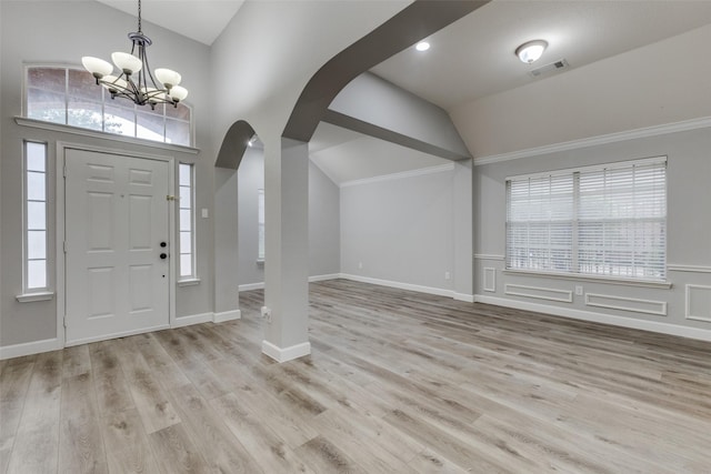 entrance foyer with a notable chandelier, arched walkways, plenty of natural light, lofted ceiling, and visible vents
