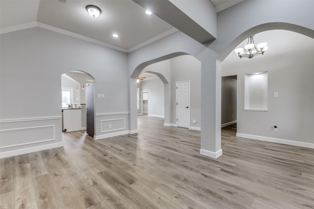 interior space with arched walkways, ornamental molding, light wood-style flooring, and a notable chandelier