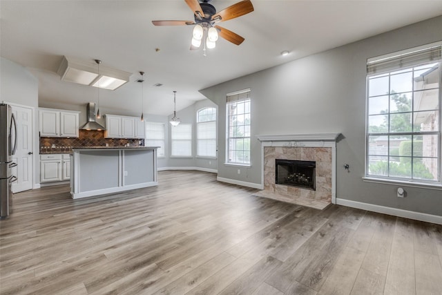 unfurnished living room featuring baseboards, a wealth of natural light, and a high end fireplace