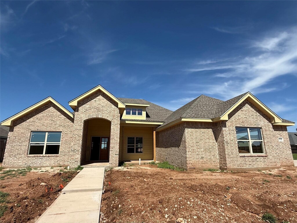 view of front facade with brick siding and a shingled roof