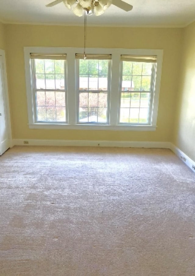 carpeted spare room with plenty of natural light, baseboards, and ceiling fan