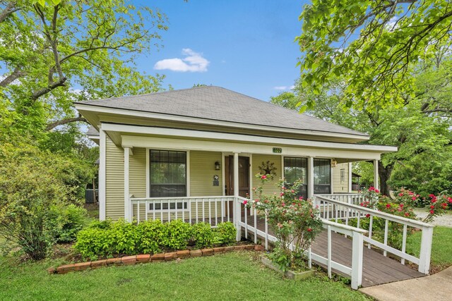 bungalow-style home with a porch, cooling unit, a shingled roof, and a front yard