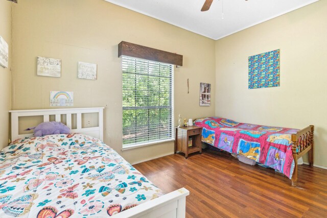 bedroom featuring ceiling fan, baseboards, multiple windows, and wood finished floors