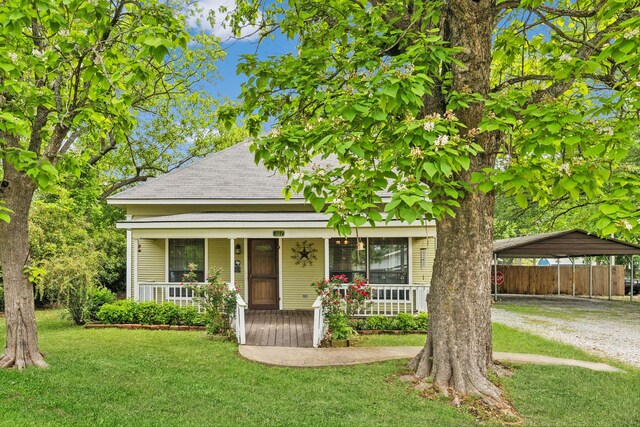 view of front of house featuring fence, covered porch, a front yard, dirt driveway, and a carport