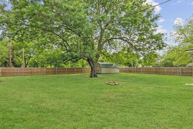 view of yard with a fenced backyard, a storage unit, and an outdoor structure