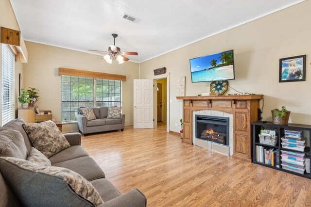 living area with a ceiling fan, visible vents, light wood-style flooring, and a fireplace