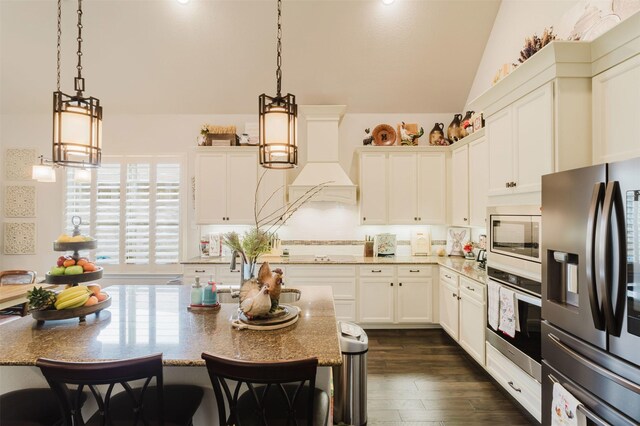 kitchen featuring dark wood-style flooring, lofted ceiling, white cabinetry, appliances with stainless steel finishes, and hanging light fixtures