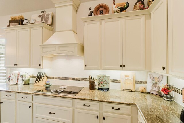 kitchen featuring white cabinets, black electric cooktop, light stone counters, and decorative backsplash
