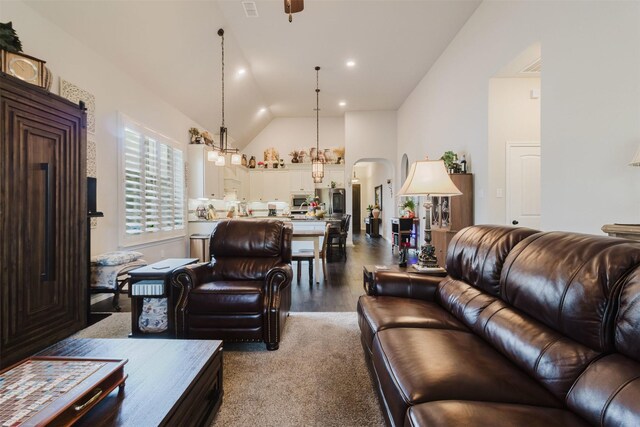 living room with arched walkways, high vaulted ceiling, wood finished floors, and visible vents