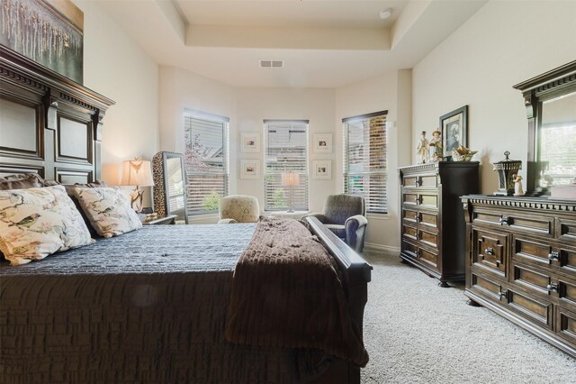 bedroom featuring visible vents, a tray ceiling, and light colored carpet
