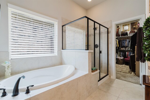 full bath with a spacious closet, a shower stall, tile patterned flooring, and a garden tub
