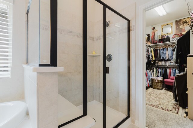 full bathroom with a bath, a spacious closet, and a shower stall