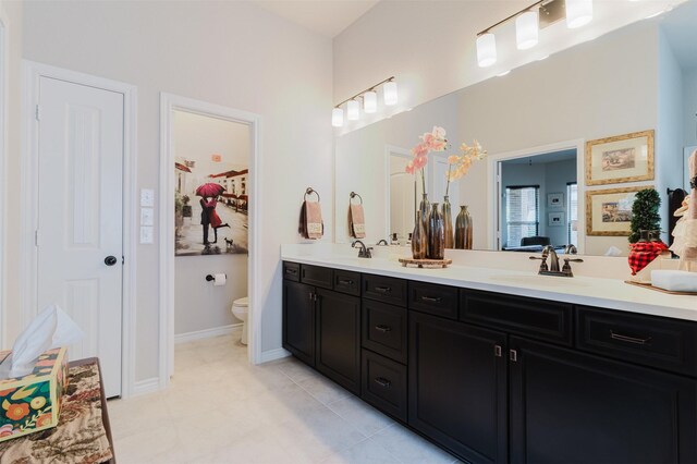 full bath with double vanity, tile patterned flooring, toilet, and a sink
