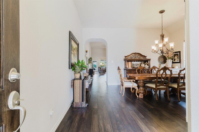 dining area with an inviting chandelier, dark wood-style flooring, baseboards, arched walkways, and vaulted ceiling