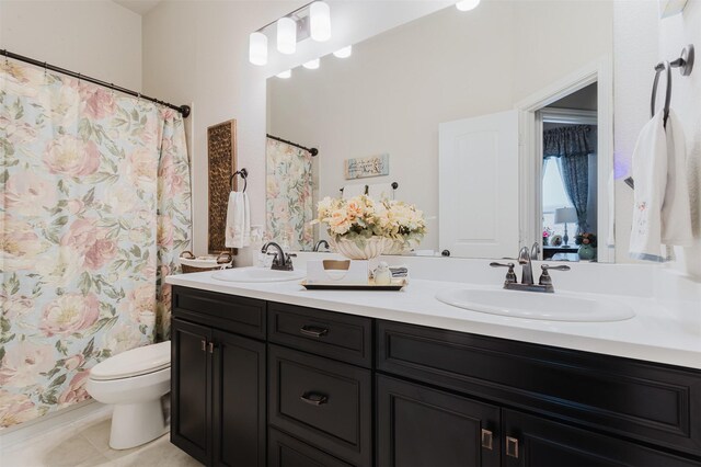 bathroom featuring double vanity, toilet, a sink, and tile patterned flooring