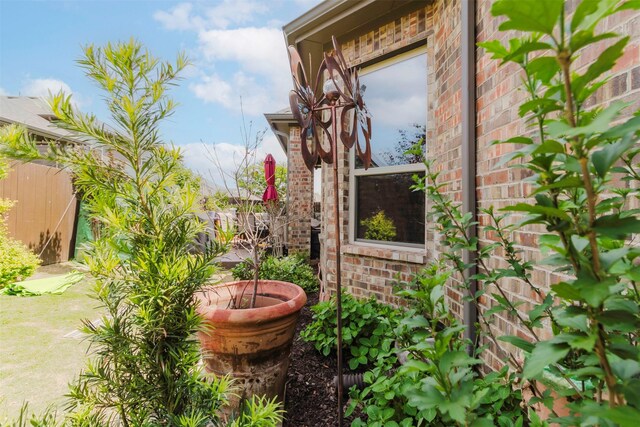 view of side of property featuring fence and brick siding