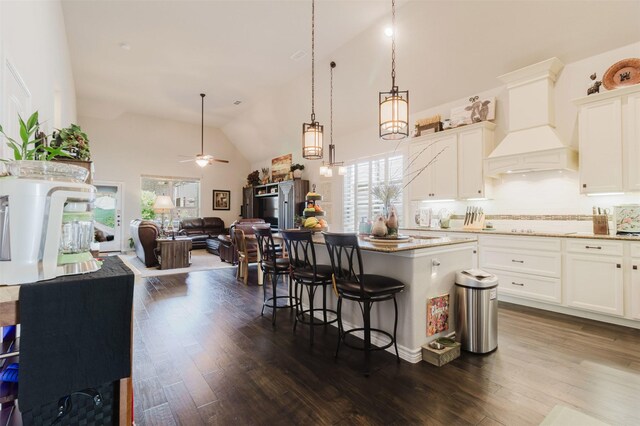kitchen with open floor plan, a wealth of natural light, premium range hood, and a kitchen bar