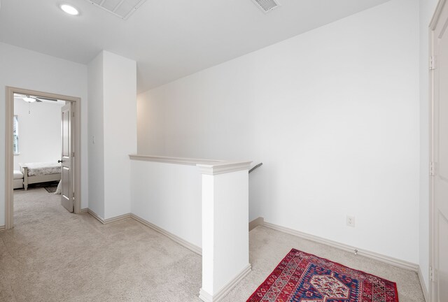 hallway featuring visible vents, carpet flooring, baseboards, and an upstairs landing