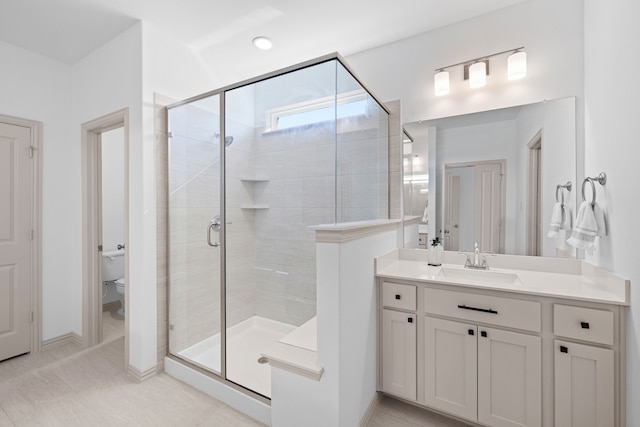 full bathroom with vanity, baseboards, a stall shower, and toilet