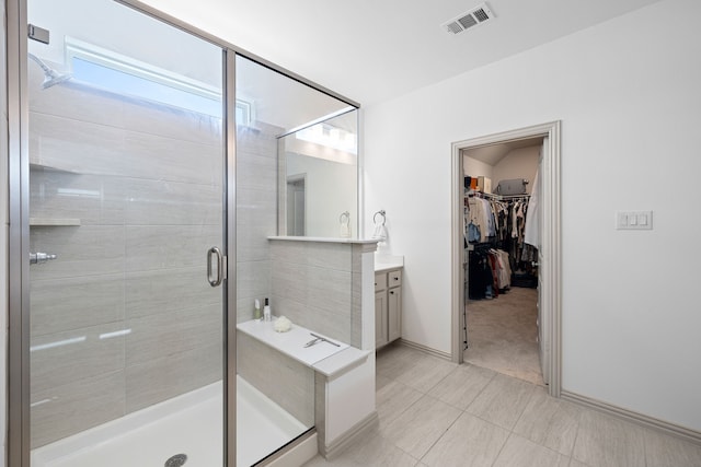full bath featuring a walk in closet, vanity, baseboards, visible vents, and a stall shower