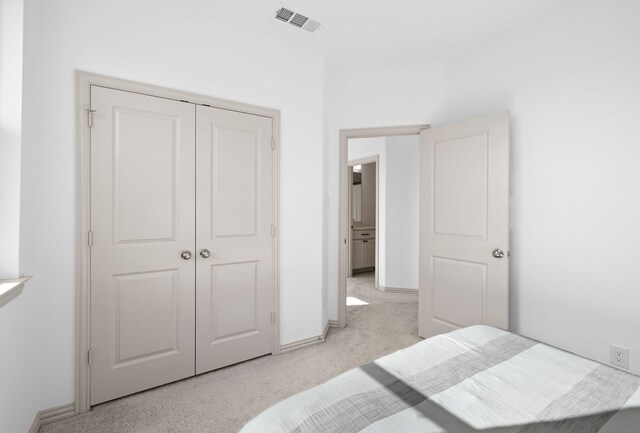 bedroom with baseboards, light carpet, a closet, and visible vents