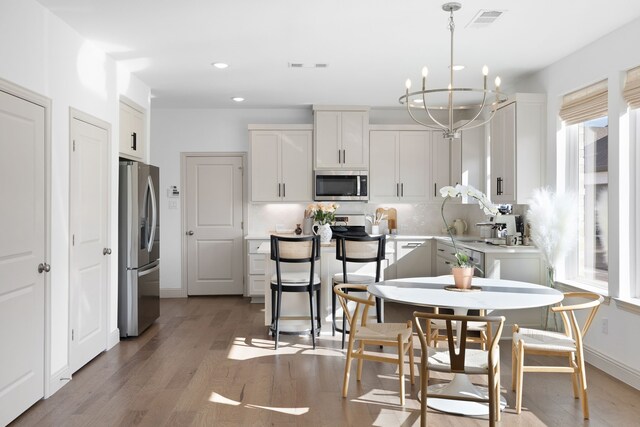 kitchen featuring light wood finished floors, stainless steel appliances, recessed lighting, and a notable chandelier