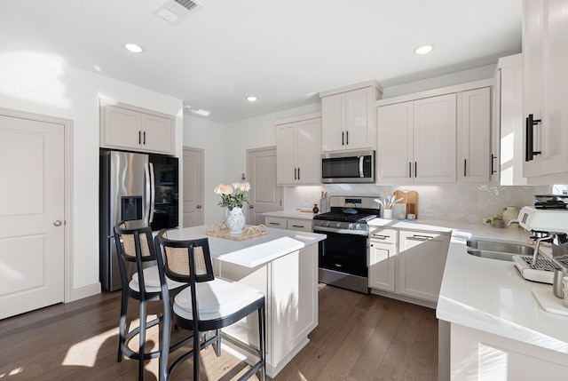 kitchen featuring decorative backsplash, visible vents, appliances with stainless steel finishes, a center island, and dark wood finished floors