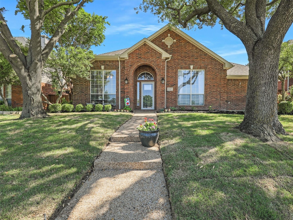 9917 Sean Dr, Frisco, TX 75035 - view of front facade featuring a shingled roof, a front lawn, and brick siding