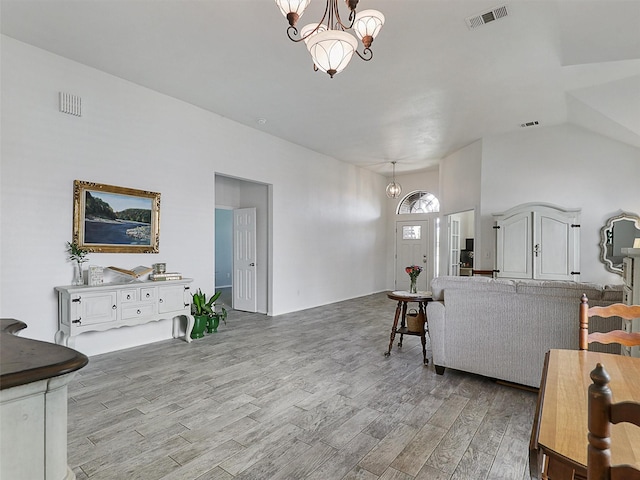 living area featuring light wood-style floors, visible vents, and an inviting chandelier