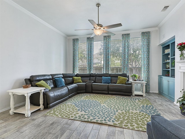 living area featuring a ceiling fan, plenty of natural light, ornamental molding, and light wood-type flooring