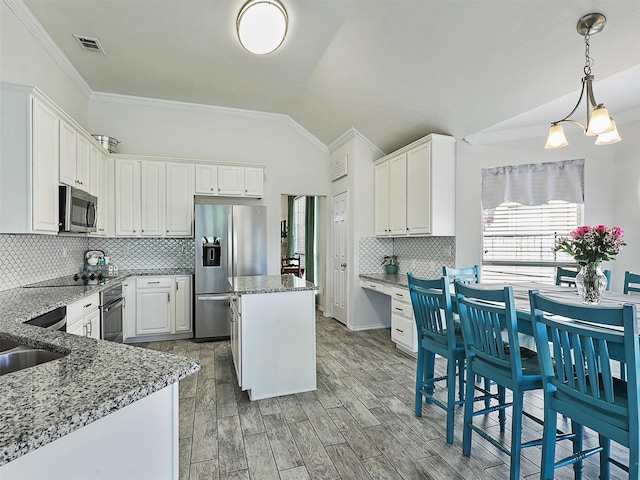 kitchen featuring visible vents, lofted ceiling, a kitchen island, light stone countertops, and black appliances