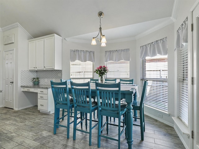dining space with crown molding, baseboards, wood finished floors, and an inviting chandelier