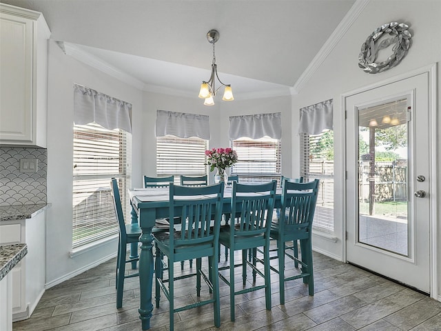 dining space featuring crown molding, a notable chandelier, light wood finished floors, and lofted ceiling