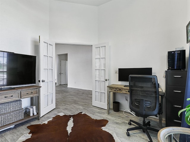 home office with a towering ceiling and wood finished floors