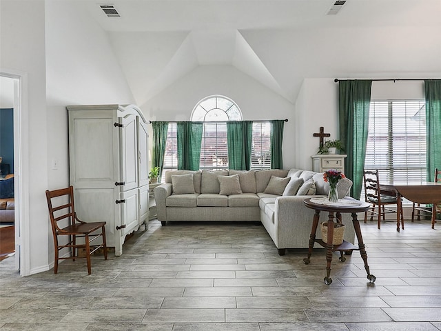 living room with vaulted ceiling, light wood-type flooring, and visible vents