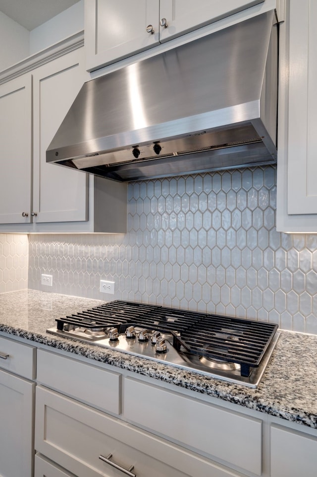 4402 Cypress Thorn Dr, Arlington, TX 76005 - kitchen featuring under cabinet range hood, stainless steel gas cooktop, decorative backsplash, white cabinetry, and light stone counters
