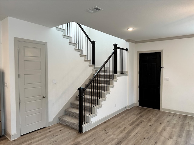 foyer featuring visible vents, baseboards, wood finished floors, and stairway