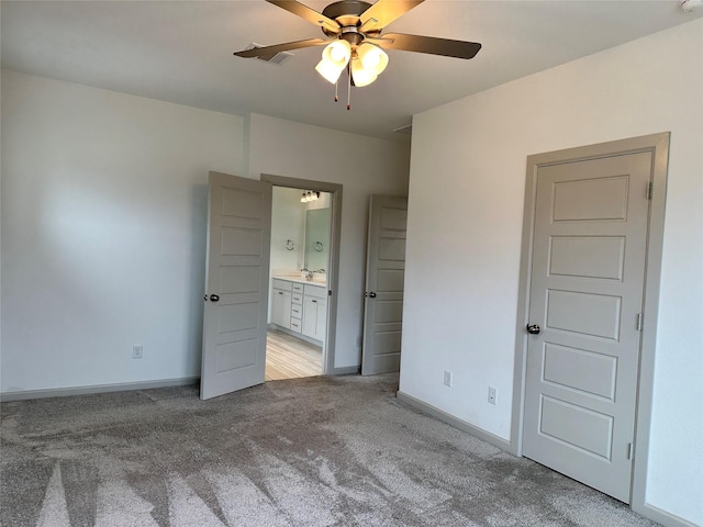 unfurnished bedroom featuring baseboards, connected bathroom, ceiling fan, and light carpet