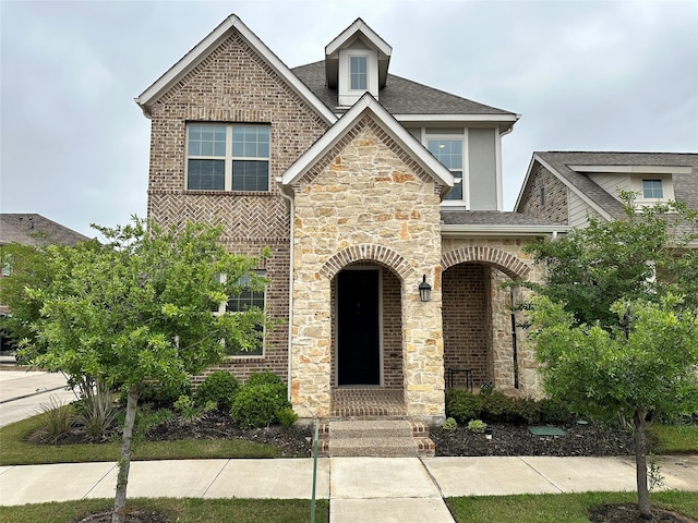 view of front of home featuring brick siding, roof with shingles, and stone siding