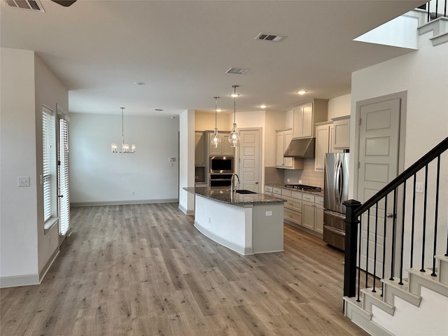 kitchen with appliances with stainless steel finishes, decorative backsplash, under cabinet range hood, and light wood finished floors
