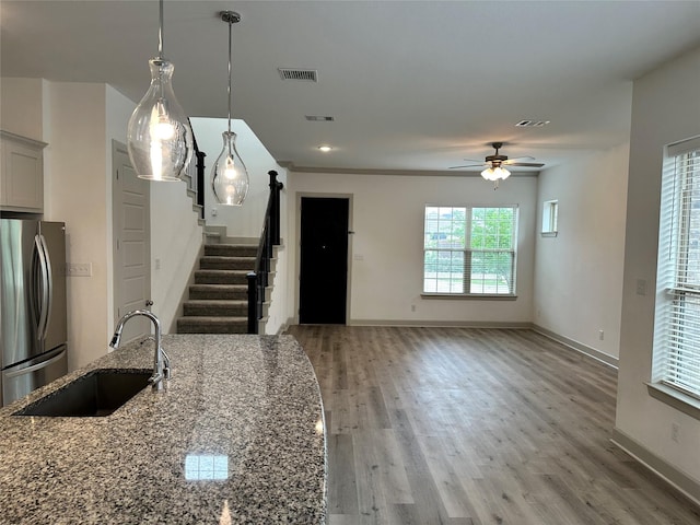 kitchen with visible vents, freestanding refrigerator, light stone countertops, ceiling fan, and a sink