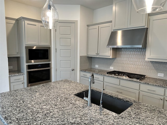 kitchen featuring dark stone counters, tasteful backsplash, stainless steel appliances, and under cabinet range hood