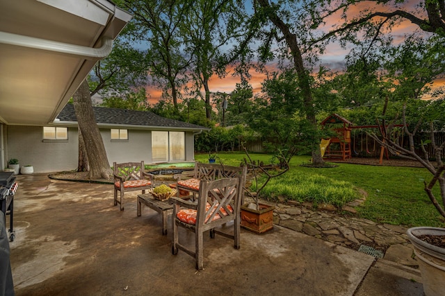 3200 Spanish Oak Dr, Fort Worth, TX 76109 - patio terrace at dusk with a playground, fence, a yard, and a fire pit