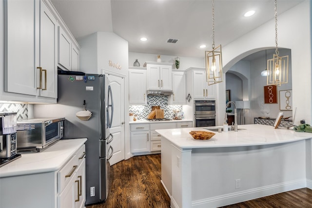 kitchen featuring decorative backsplash, appliances with stainless steel finishes, a sink, a chandelier, and dark wood-type flooring