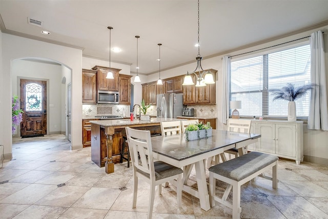 8357 Blue Periwinkle Ln, Fort Worth, TX 76123 - kitchen featuring visible vents, ornamental molding, brown cabinetry, arched walkways, and appliances with stainless steel finishes