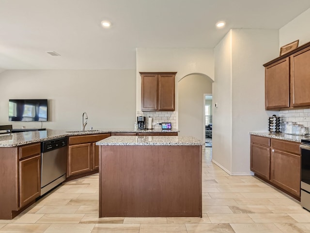 kitchen featuring arched walkways, tasteful backsplash, a kitchen island, and stainless steel appliances