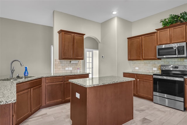 5320 Creek Hill Ln, Fort Worth, TX 76179 - kitchen featuring appliances with stainless steel finishes, a sink, arched walkways, light stone countertops, and a center island