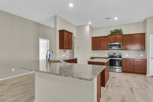 5320 Creek Hill Ln, Fort Worth, TX 76179 - kitchen with stainless steel appliances, a sink, a peninsula, light wood finished floors, and decorative backsplash