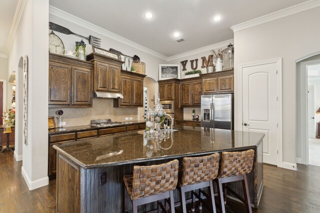 kitchen with crown molding, dark wood-style floors, tasteful backsplash, arched walkways, and appliances with stainless steel finishes