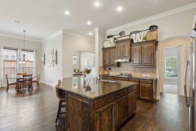 kitchen with a sink, arched walkways, dark wood-style floors, and stainless steel appliances